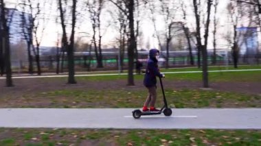 Maskeli kız elektrikli scooter kullanıyor. Kiev, Ukrayna