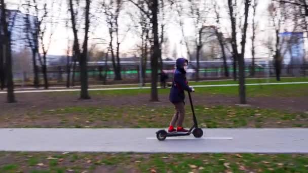 Maskiertes Mädchen fährt auf Elektroroller. Kiew, Ukraine — Stockvideo