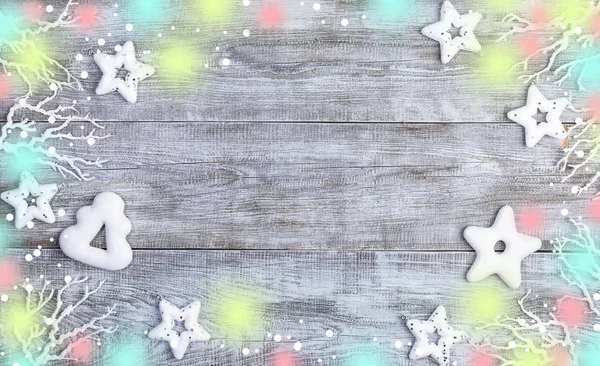 Świąteczne dekoracje. Rama białych gwiazd Bożego Narodzenia, pierniki, gałązki, śnieg i światła na białym drewnianym tle. — Zdjęcie stockowe
