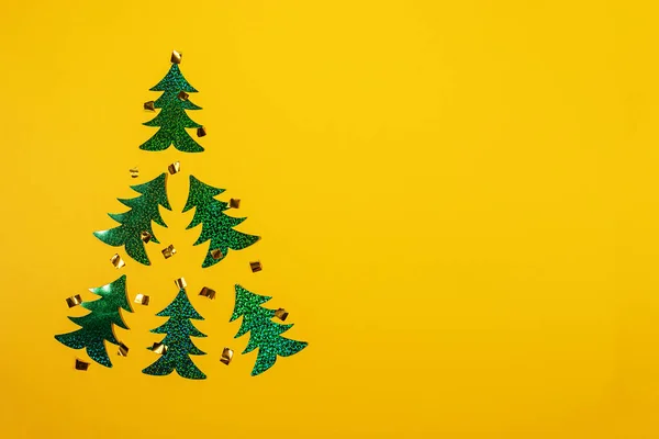 Altı parlak yeşil holografik Noel ağacından oluşan Noel ağacıyla modaya uygun sarı renkli asgari Noel modeli.. 