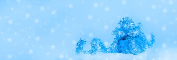 Slavnostní vánoční banner v barvě 2020 Classic Blue. Dárková krabička zdobené tinsel ve sněhu na pozadí se sněhem. — Stock fotografie
