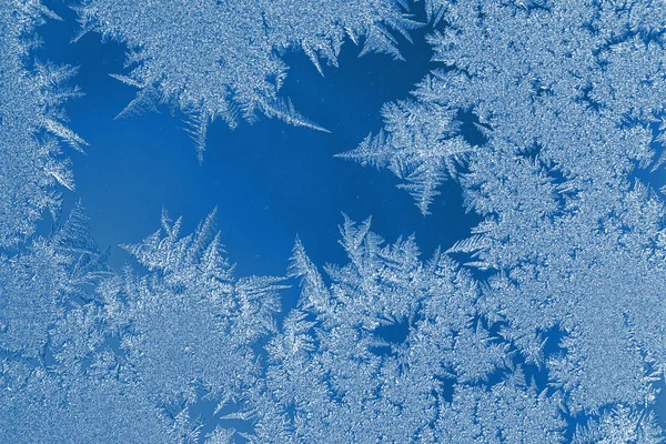 Winter Weihnachten natürlicher Hintergrund in der Trendfarbe 2020 klassisch blau. schönes frostiges Muster auf Fensterglas. — Stockfoto