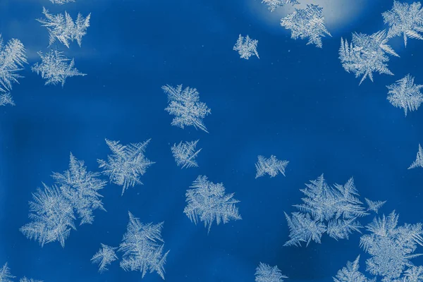 Зимовий природний фон в модному кольорі 2020 року Classic Blue. Морозний візерунок як загострені сніжинки на віконному склі . — стокове фото
