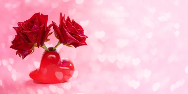 Nahaufnahme von drei roten Rosen in rotem vasenförmigem Herz auf rosa Bokeh-Hintergrund mit Herzen. Valentinstag oder Muttertag Festbanner. — Stockfoto