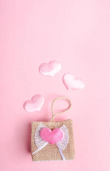 Kleine dekorative Weidenhandtasche und drei fliegende rosa Herzen auf rosa Hintergrund. Valentinstag-Konzept. — Stockfoto