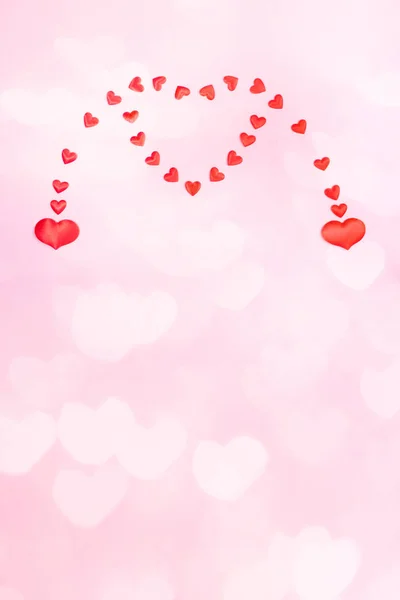 Walentynki lub wesele pionowe świąteczne różowe tło z sercami bokeh. Dwa małe serca łączą się w jedno wielkie serce. — Zdjęcie stockowe