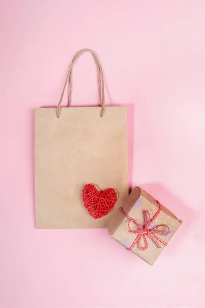 День Святого Валентина макет з паперовим мішком, загорнута подарункова коробка і червоне серце на рожевому тлі. святкову концепцію Zero Waste . — стокове фото