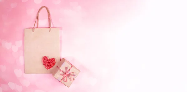 Valentinstag-Festbanner. Geschenkbox, Papiertüte, rotes Weidenherz auf rosa Bokeh-Hintergrund mit Herzen. — Stockfoto