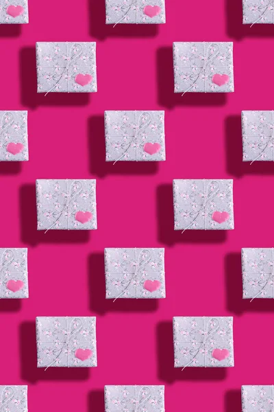 Patrón sin costuras de cajas de regalo, envueltas en papel gris con patrón floral con corazones de color rosa y sombras en rosa brillante . — Foto de Stock