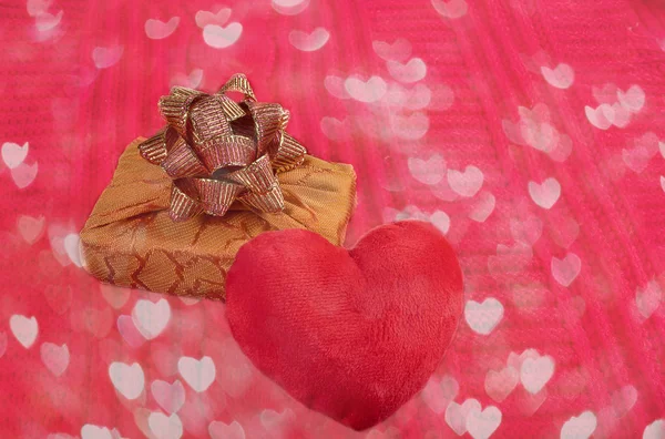 Valentinstag heimelige gemütliche Kulisse. Nahaufnahme-Plüschherz und Geschenkschachtel auf rotem Strickstoff mit Herzen Bokeh. — Stockfoto