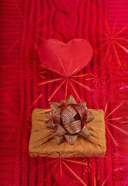 Valentines day homely cosy background. Plush heart and wrapped gift box on red knitted cloth with asterisks overlay. — Stock Photo, Image