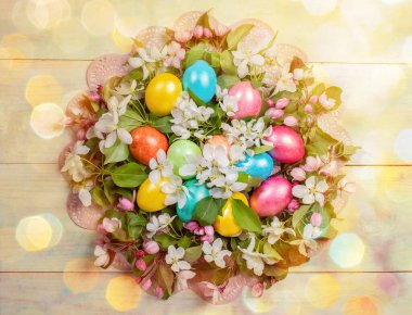 Paskalya bayramı, renkli Paskalya yumurtaları ve beyaz ve pembe elma ağaçlarından oluşan dallar ahşap arka planda, altıgen bokeh ile açılışı yapılan pembe peçeteler. Üst görünüm.