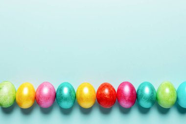 Parlak renkli Paskalya yumurtaları. Moda Neo Mint pastel arka planında koyu gölgeler var. Paskalya bayramı boş planı. Üst görünüm, düz görünüm, kopyalama alanı.