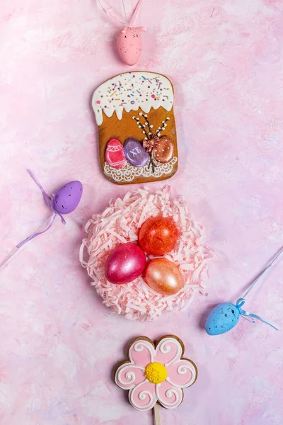 Пасхальный праздничный вертикальный фон с цветными яйцами в декоративном гнезде и декоративных пасхальных яиц, пасхальные пряники на розовом фоне . — стоковое фото