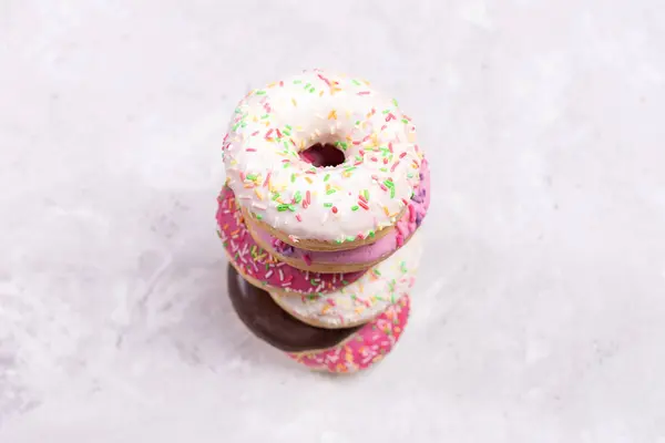Vista superior para empilhar de seis donuts com esmalte multicolorido no centro de fundo de concreto desfocado. Foco seletivo . — Fotografia de Stock