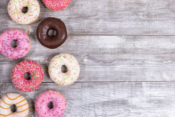 Geleneksel donutlar beyaz boyalı ahşap masaya serilmiş çok renkli jöleli çörekler. Donut - geleneksel tatlı pasta. Üst manzara, düz yatış. Metin için alanı kopyala.