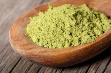 Tahta kaşık üzerinde eski ahşap tahta üzerinde Japon yeşil kibrit çay tozu. Kibrit çayı organik ve sağlıklı bir üründür. Antioksidan kaynağıdır. Yakın çekim, seçici odaklanma.