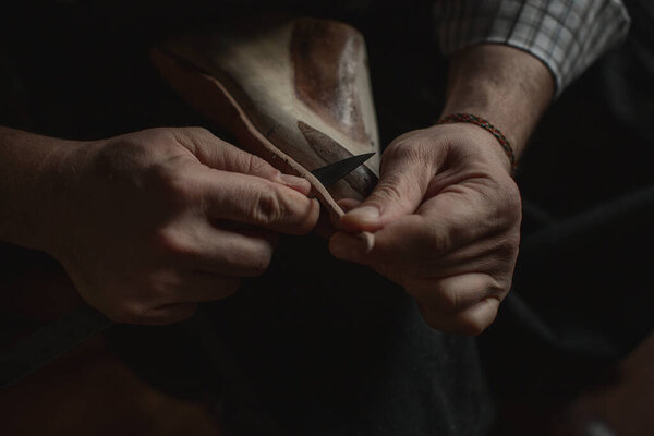 The hands of the shoemaker at work make the sole for new handmade shoes. The process of creating shoes
