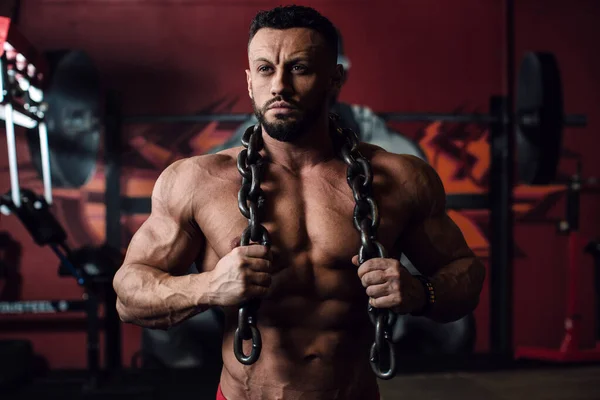 Spor salonunun arka planında çıplak gövdeli esmer bir erkek.