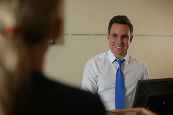 Uma recepcionista sorridente encontra um hóspede do hotel. Registo do cliente — Fotografia de Stock