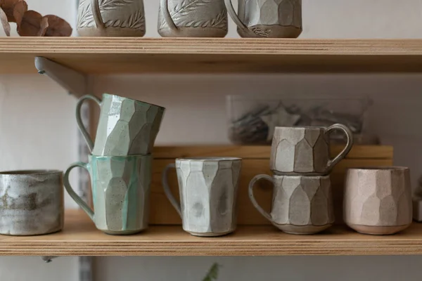 Niezwykłe ręcznie robione kubki ceramiczne na półce w garncarni — Zdjęcie stockowe