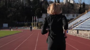 Kız stadyumdaki koşu bandında koşuyor..