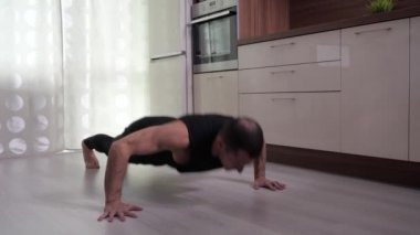Bir adam evde yerden şınav çeker..
