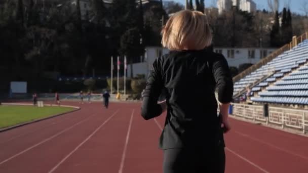Menina corre em uma esteira no estádio . — Vídeo de Stock