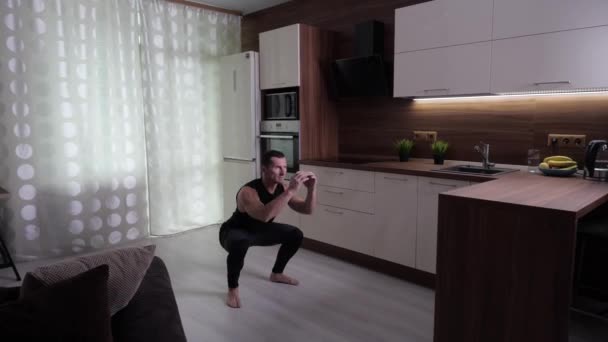 The athlete trains hard at home, performing jumps from the squat — Stock Video