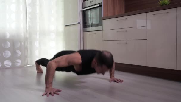 Een man voert push-ups uit vanuit de vloer thuis. — Stockvideo