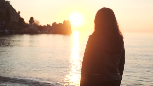 Una ragazza si trova sulla riva del mare e gode del tramonto . — Video Stock