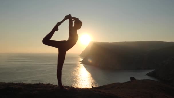 Jong meisje is stretching op de achtergrond van de zee en de bergen bij zonsopgang — Stockvideo