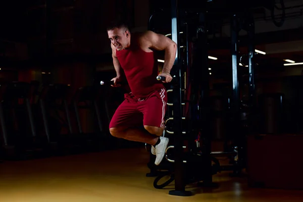Spor salonunda paralel barlarda şınav çeken genç bir sporcu.