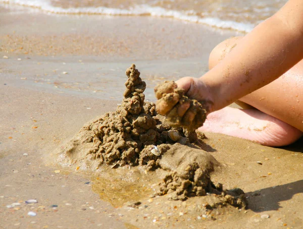 Sand castle made of sand by the hands of a child on the shore.