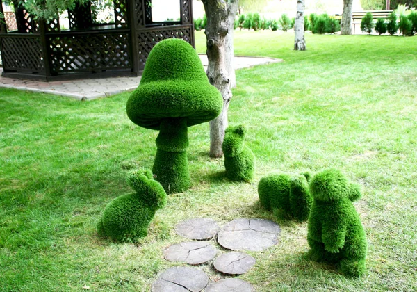 Tavşan heykelleri ve parkta yeşil polimer otlardan yapılmış bir mantar..
