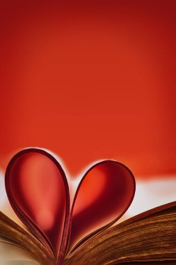 Kırmızı aksanlı soyut bir arkaplan. Eski bir kitap. Katlanmış çarşaflardan katlanmış kalbi olan açık bir kitap. Eğitim kavramını seviyorum. Bulanık kalplerin arkaplanını kitap sayfalarından özetle. Boşluğu kopyala