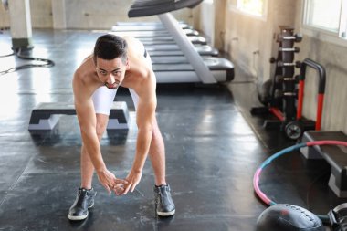 Bıyıklı yakışıklı beyaz adam spor salonunda esneme egzersizi yapıyor.