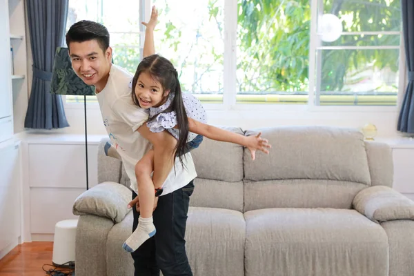 Samotny rodzic szczęśliwy rodzinny portret. Azjatycki ojciec trzymał córkę, gdy stał w salonie. Samotny ojciec dobrze się bawi, a jego córeczka się śmieje. Szczęśliwa koncepcja rodziny. — Zdjęcie stockowe