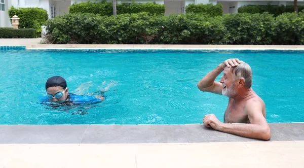 Feliz anciano caucásico marido y anciano asiático esposa nadando en piscina durante las vacaciones de jubilación con relajación en día soleado — Foto de Stock