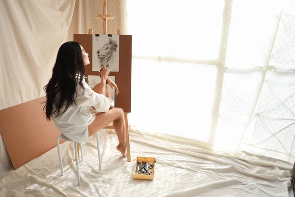Femme artiste en chemise blanche penser quelque chose tout en dessinant image avec crayon (concept de style de vie femme) — Photo