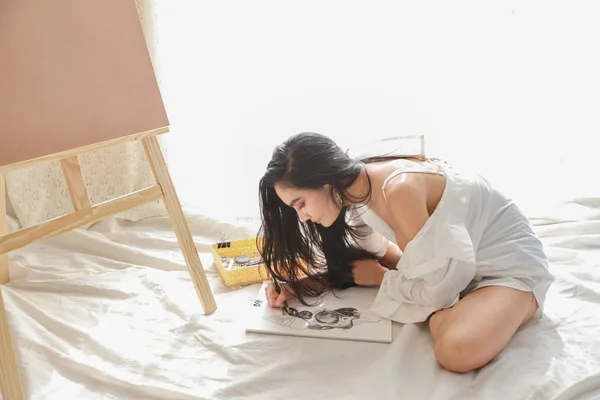 Asiatique femme artiste en blanc chemise dessin image avec crayon dans salon (femme style de vie concept) — Photo