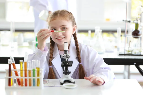 Niña curiosa está experimentando la ciencia con microscopio y cara de atención (concepto de educación y científico) — Foto de Stock