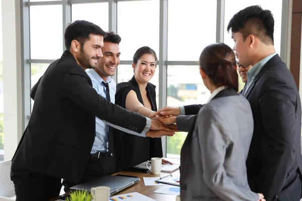 Medium shot multietnisk affärsfolk stadning i office mötesrum och stapla händerna tillsammans innebörden av lagarbete koncept med glada leende ansikte — Stockfoto