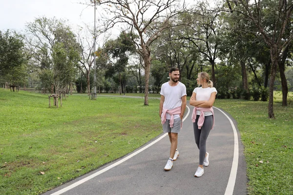 年轻的亚洲夫妇穿着运动服在夏季户外公园散步。 （健康的或友谊的情人节概念) — 图库照片