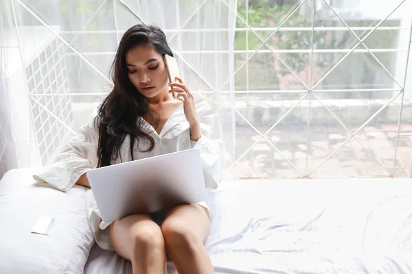 Adulto freelance asiático mujer en blanco camisa trabajo en computadora y celular en dormitorio con belleza cara —  Fotos de Stock