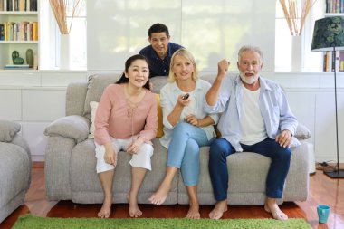 Oturma odasında oturmuş televizyon seyreden ve haykırarak iyi haberlerle şok olan çok ırklı ve çok ırklı üst düzey insanlar. Dört arkadaş canlısı karışık ırk gülümseyerek eğleniyor