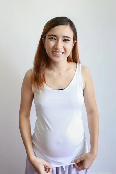 Longitud completa disparo joven asiático embarazada vientre en blanco vestido con feliz sonriente cara retrato y de pie sobre blanco fondo — Foto de Stock