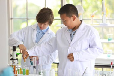 Çok ırklı uluslararası okul öğrencilerinden oluşan orta sınıf grup, mutlu gülümseyen yüzlü renkli test tüpünde bilimsel deneyler yapıyorlar (eğitim kavramı)) 