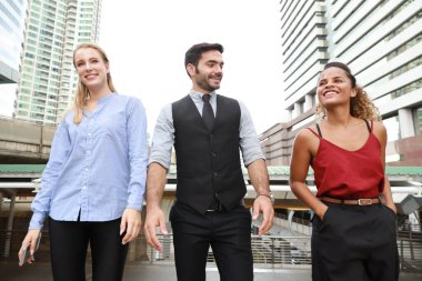 Mutlu gülümseyen Kafkasyalı genç işadamı ve iş kadını gayri resmi giyimi, öğle arasında şehir manzarası arka planında yürürken tartışıyorlar ve proje hakkında tartışıyorlar.