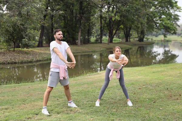 图为夏季在公园里 一对年轻的高加索夫妇在户外运动 伸展身体 脸上挂着笑脸 绿树成荫 — 图库照片